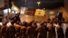 Supporters of the Iran-backed militant group hold the flags of Shiite Hezbollah and Amal Movement groups, as they stand in front of Lebanese army soldiers who divided between them and the anti-government protesters after a clashes erupted between them, in Beirut, Lebanon, early M