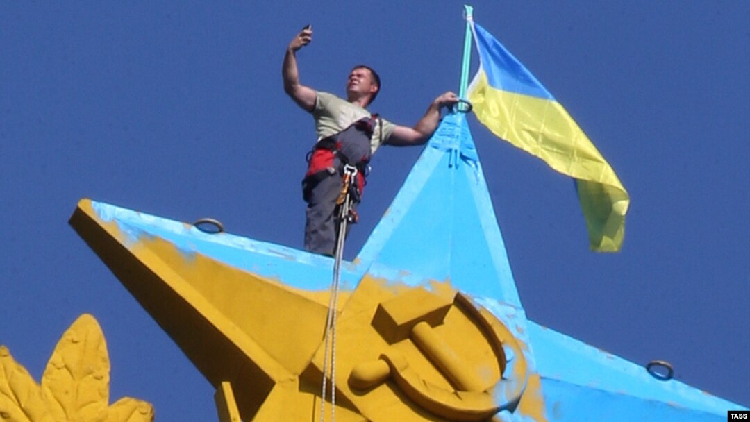 A Moscow city worker takes a selfie while atop the Kotelnicheskaya Embankment building in Moscow to remove the Ukrainian flag mounted there overnight on August 19-20. The hammer-and-sickled star and laurel wreath was also painted in Ukrainian colors. 