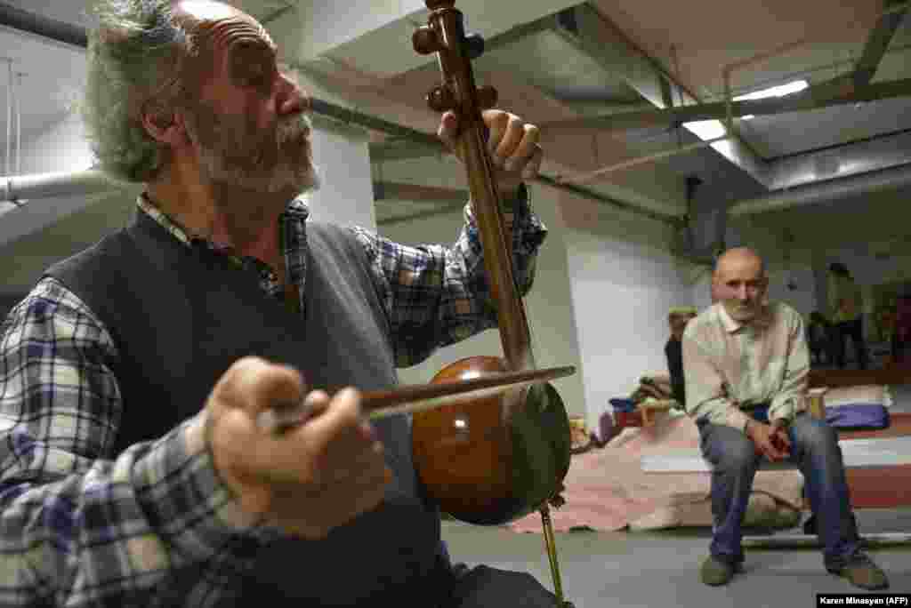 Armenian musician Hakob Khalatian plays his kamancha string instrument in a bomb shelter in Stepanakert on November 5.&nbsp;