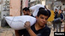 Cetățeni palestinieni se aprovizionează cu saci de făină pe măsură ce atacurile aeriene ale Israelului duc spre o criză umanitară de proporții în Gaza.