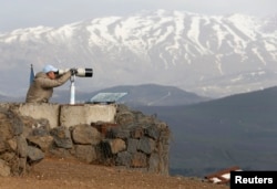 Pripadnik Posmatračkih snaga Ujedinjenih nacija (UNDOF) u januaru 2015. gleda kroz dvogled planinu Bental na Golanskoj visoravni koju je Izrael okupirao u čestodnevnom ratu sa Sirijom 1967. a zatim aneksirao 1981.