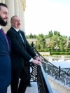 Azerbaijani President Ilham Aliyev (right) and Syria's interim president, Ahmad al-Sharaa, stand on a balcony during their meeting in Baku on July 12