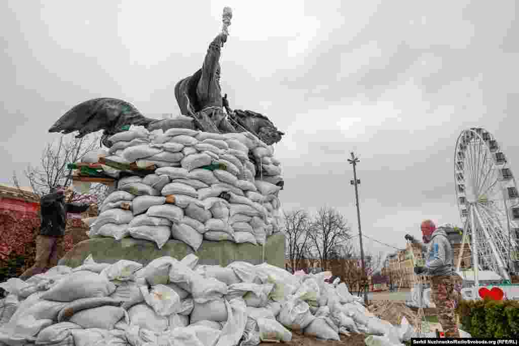 Люди обкладають мішками з піском памʼятник Петрові Сагайдачному, щоб захистити від пошкоджень при обстрілах. Київ, 26 березня 2022 року