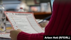 Një zyrtare e Komisionit Qendror Zgjedhor duke mbajtur në dorë një fletëvotim gjatë rinumërimit të votave për zgjedhjet e parakohshme të 28 dhjetorit të hënën e 19 dhjetorit në Prishtinë.