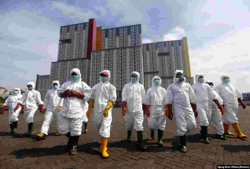 Indonesian Red Cross Society personnel walk in protective suits during an operation to spray disinfectant at the Kemayoran Athletes Village, to prevent the spread of coronavirus disease (COVID-19) in Jakarta, Indonesia