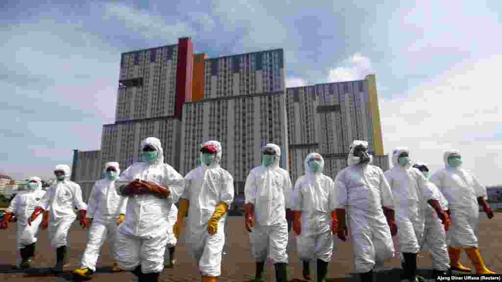 Indonesian Red Cross Society personnel walk in protective suits during an operation to spray disinfectant at the Kemayoran Athletes Village, to prevent the spread of coronavirus disease (COVID-19) in Jakarta, Indonesia