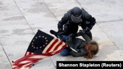 Капитолийга ҳужум қилган Трамп тарафдорларидан бирини полициячи қўлга олмоқда, январь, Вашингтон, АҚШ