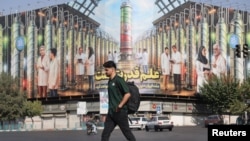 Një person kalon pranë një bilbordi ku shfaqen fotografitë e shkencëtarëve bërthamorë iranianë të vrarë gjatë sulmeve izraelite. Teheran, 29 gusht 2025. 