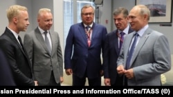 Nikita Mazepin (left) and Dmitry Mazepin (2nd left) speak with Russian President Vladimir Putin (right) at the 2018 Formula One Russian Grand Prix final day events at the Sochi Autodrom racing circuit in September 2018. 