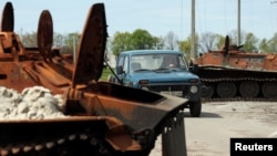 A man drives his car among destroyed Russian armor in a village near Kharkiv on May 11. 