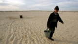 A Kazakh villager carries a bucket of water from a well in a desert that once formed the bed of the Aral Sea. (file photo)