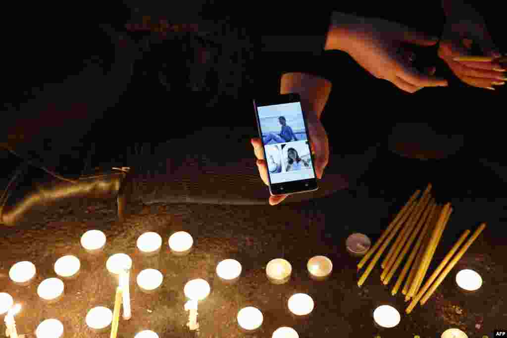 An Iranian holds a phone bearing the portraits of victims killed in the crash of Ukraine International Airlines Flight 752 during a gathering in front of Amir Kabir University in the capital, Tehran, on January 11. (AFP)