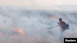 Një burrë përpiqet t'i shuajë zjarret pas sulmit raketor nga Libani në jug të Izraelit, 20 shtator 2024.