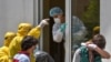 Armenia -- A hospital worker (C) wearing a protective face mask and outfit, speaks with two ambulance doctors wearing yellow protective suits at the Grigor Lusavorich Medical Center in Yerevan, May 27, 2020