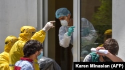 Armenia -- A hospital worker (C) wearing a protective face mask and outfit, speaks with two ambulance doctors wearing yellow protective suits at the Grigor Lusavorich Medical Center in Yerevan, May 27, 2020