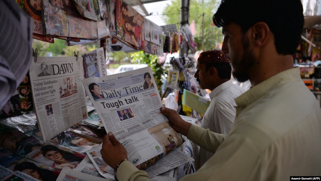 Pakistanis read newspapers with a front page headline about U.S. President Donald Trump at a stall in Islamabad on August 23.