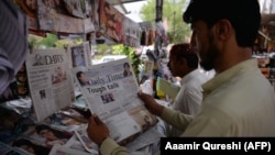 Pakistanis read newspapers with a front page headline about U.S. President Donald Trump at a stall in Islamabad on August 23.