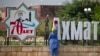 Уборщица на фоне городских украшений в честь 70-летия Ахмата Кадырова, архивное фото