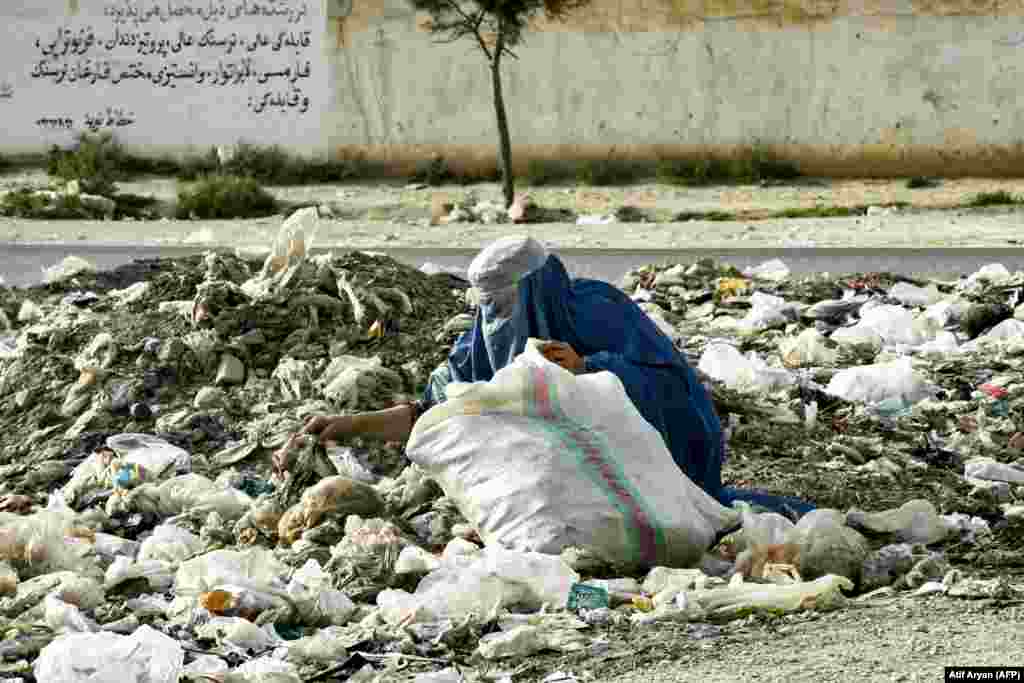 An Afghan woman searches for recyclable materials amid plastic waste at a garbage dump on the outskirts of Mazar-e Sharif.&nbsp;