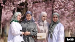 Femei pozând printre florile de cireș în apropierea Moscheei Ahmad Kadîrov din Groznîi în aprilie 2024.