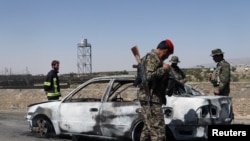 Afghan security forces inspect the exterior of a car after a suicide bomb blast in Gardez, Paktia Province on June 18.