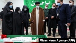 The head of Iran's judiciary, Ayatollah Ebrahim Raisi (center), pays respects to slain scientist Mohsen Fakhrizadeh along with his family in Tehran on November 28.