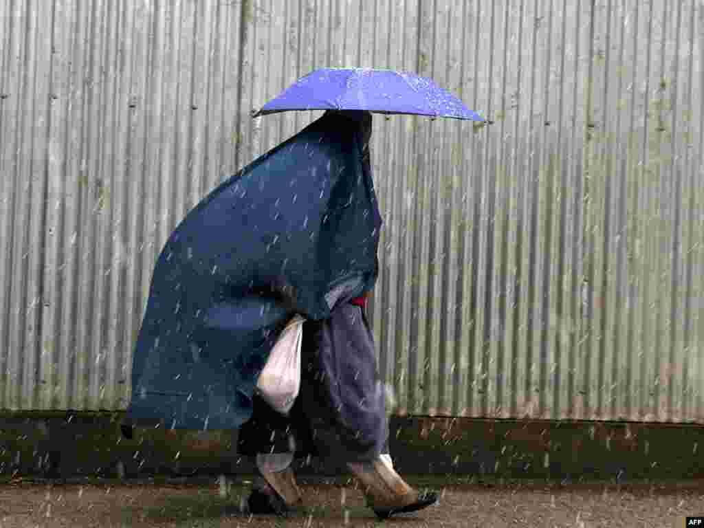 A woman walks with an umbrella during snowfall in the Afghan capital, Kabul, on March 3. Photo by Massoud Hossaini for AFP