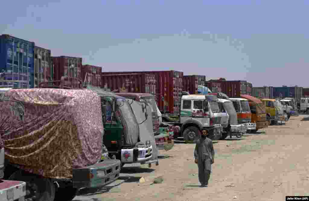 Водитель проходит мимо направляющихся в Афганистан грузовиков, застрявших на пограничном переходе Чаман