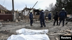 Radnici hitnih službi stoje pored tijela pronađenih u ruševinama zgrade pogođene u ruskim napadima dronom u Zaporižju, Ukrajina, 21. marta.