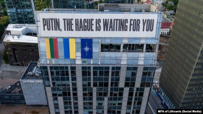 Банер «Путін, Гаага чекає на тебе» поруч із прапорами Литви, України та НАТО, Вільнюс, Литва, 21 серпня 2024 року
