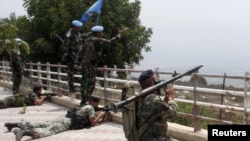 Lebanese soldiers take positions as UN peacekeepers gesture toward Israeli soldiers at the Lebanese-Israeli border in Adaisseh village in August 2010.