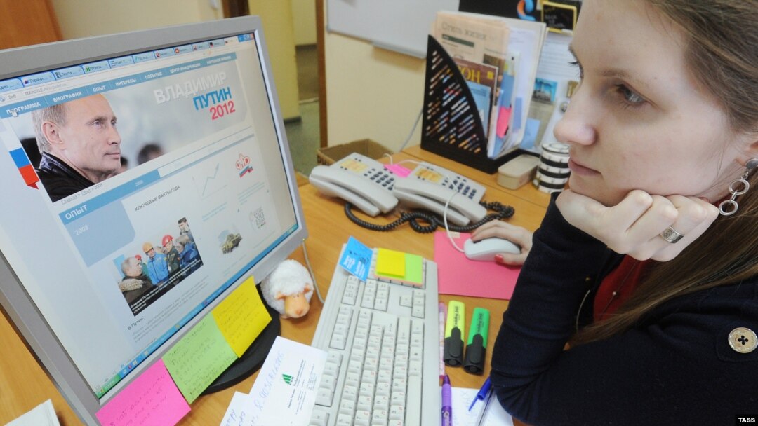 A woman looks at a computer monitor displaying the main page of Prime Minister Vladimir Putin's election campaign website.