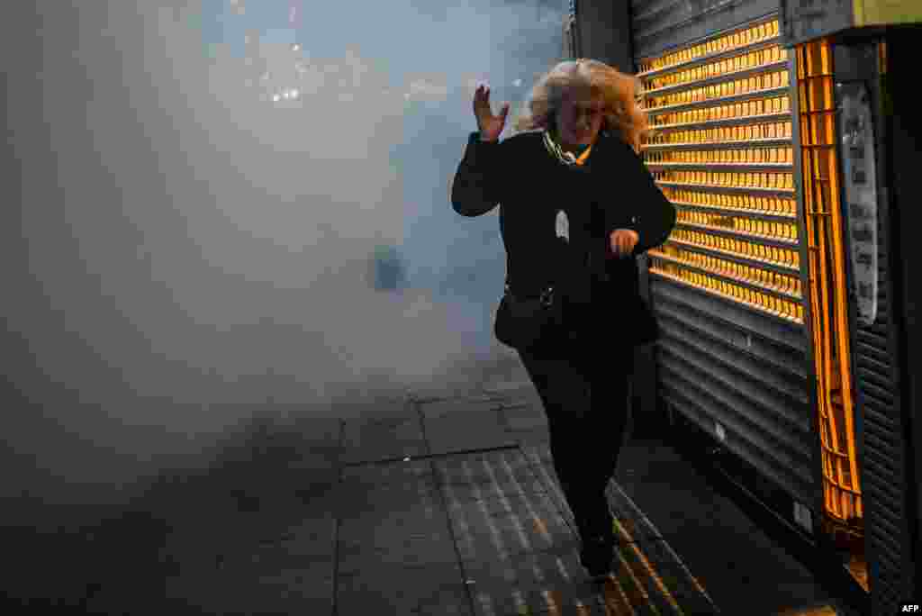 A woman runs away as Turkish riot police use tear gas to disperse demonstrators during a protest against a call for the country to adopt a religious constitution in Istanbul on April 26. (AFP/Ozan Kose)