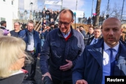 Liderul creștin-democraților germani, Friedrich Merz, stânge mâna unei alegătoare înainte să voteze în alegerile parlamentare germane, la o secție din Arnsberg, 23 februarie 2025