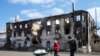 People walk past a destroyed building in the town of Vuhlehirsk, north-east from Donetsk, March 8, 2015