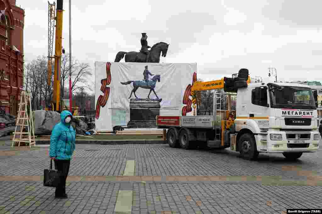 A masked woman looks over the scene on March 20. City authorities said the replica is only temporary and the original statue will be reinstalled by early May.&nbsp;