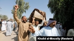 Mourners carry a coffin containing a victim of rocket attacks in the Abu Ghraib district on the outskirts of Baghdad on September 29.