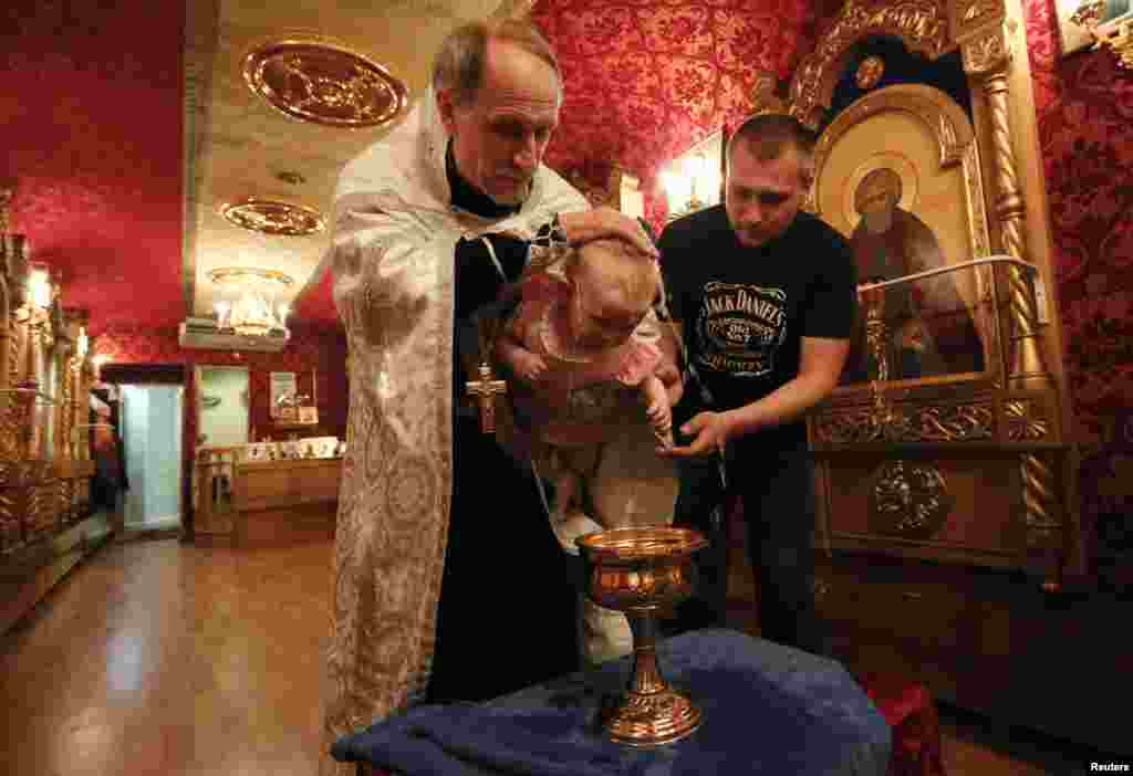 An Orthodox priest baptizes a baby at a church inside the Doctor Voino-Yasenetsky Saint Luka train, which serves as a free consultative and diagnostic medical centre, at a railway station of Divnogorsk, outside the Siberian city of Krasnoyarsk. (Reuters/Ilya Naymushin)