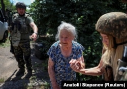 An 87-year-old resident of Druzhkivka is assisted during her evacuation from the town on June 20.