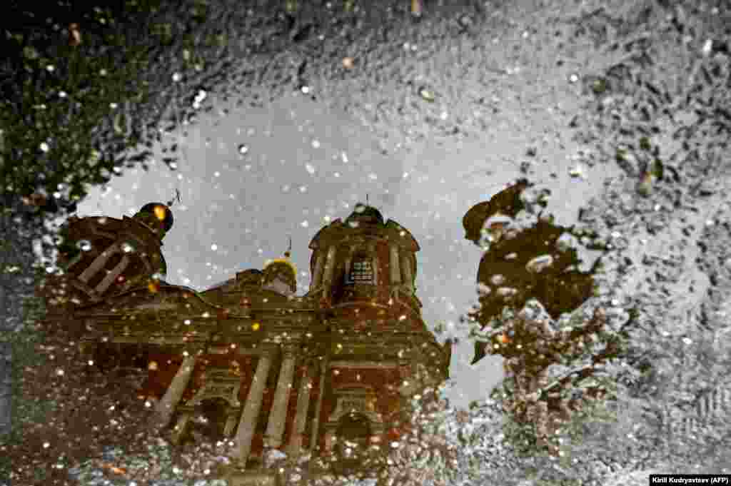 A man is reflected in a puddle as he walks past St. Clement&#39;s Church in Moscow. (AFP/Kirill Kudryavtsev)