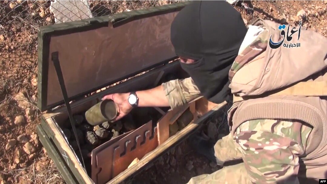 A video grab purportedly shows an IS militant displaying the contents of a crate of grenades reportedly intended for Kurdish militias but which fell into the hands of Islamic State militants near the town of Kobani.