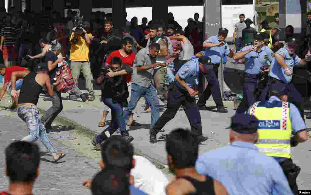 Croatian policemen run as Syrian and Afghan migrants clash at the train station in Beli Manastir on September 18.