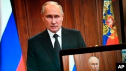Russian President Vladimir Putin is seen on monitors as he addresses the nation in Moscow on June 24 after Yevgeny Prigozhin, leader of the Wagner private mecernary group, called for armed rebellion and reached the southern city of Rostov-on-Don with his troops.