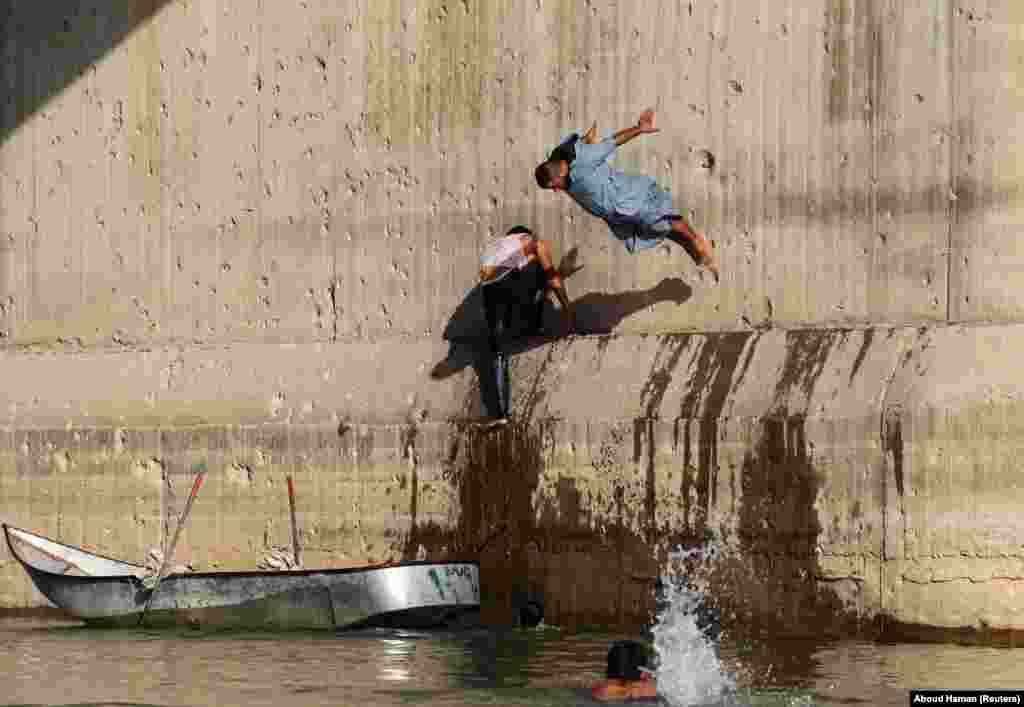 A man jumps in the Euphrates River during hot weather in Raqqa, Syria. (Reuters/Aboud Hamam)