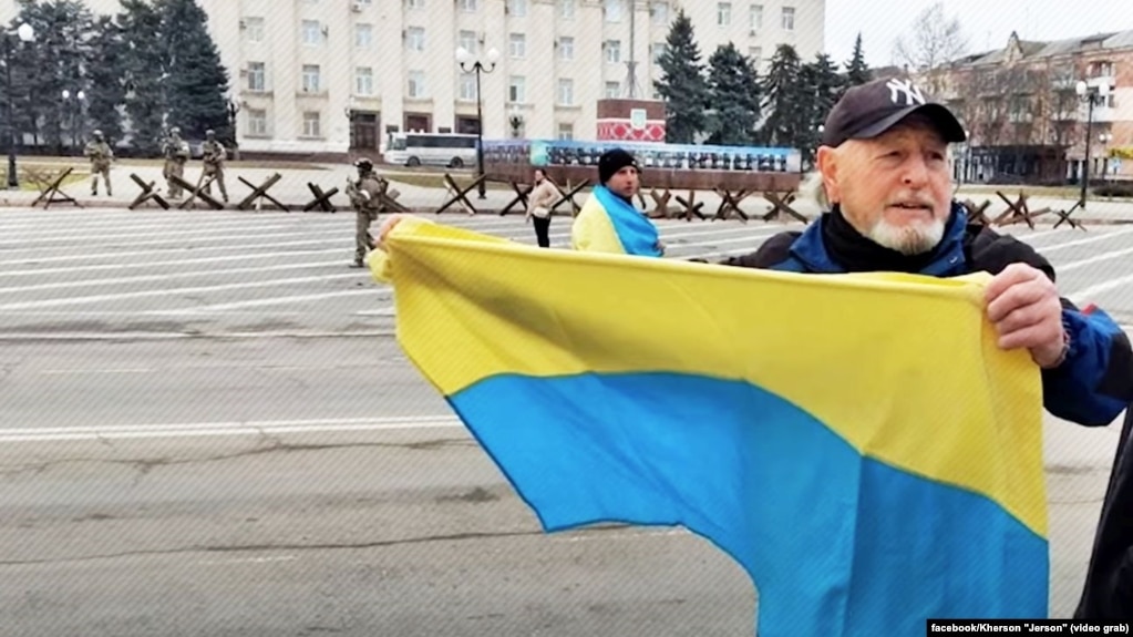 Маріано Гарсія Калатаюд – іспанський волонтер, якого викрали під час російської окупації Херсону. На світлині він на акції протесту в Хесрсоні, а ліворуч на задньому плані військові РФ