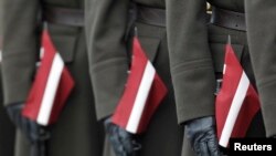 Soldați ai armatei letone au puști împodobite cu steagul național al Letoniei în timpul paradei militare cu ocazia sărbătoririi Zilei Independenței în Riga