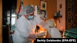 An elderly woman receives a vaccine shot against COVID-19 at her home in Kyiv on April 20.