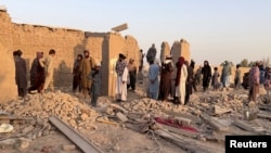 Residents stand amid the rubble of a house damaged in a Pakistani air strike on the Garmsir district of Afghanistan's Helmand Province on October 1.  