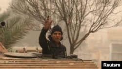 A rebel fighter gestures while riding a military vehicle is western Aleppo. (file photo)