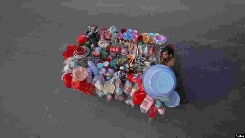 A vendor pushes a cart displaying plastic containers and accessories on a street in Lahore, Pakistan. REUTERS/Mohsin Raza